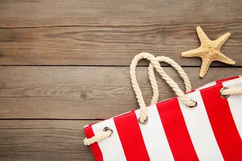 Red summer bag with seashells on grey wooden background Stock Photos