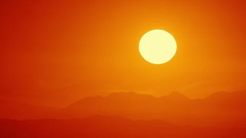 Red sun gently coloring the mountains in gradient shades of yellow and orange. Stockbeeldmateriaal 282009613
