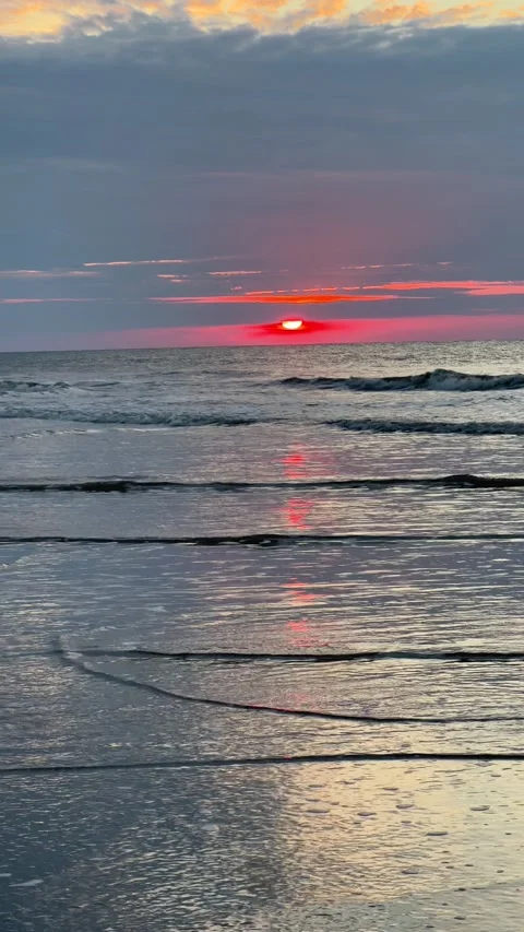 The red sun getting brighter as it starts to rise over the beach Video stock 196928087