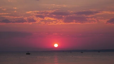 Red sun light reflects off clouds as sun sets over mediterranean ocean Video stock 97975092
