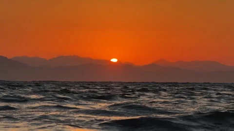 Red Sun Rising over Mountain Range Silhouette across the sea. Beautiful nature Stock Footage 341910101