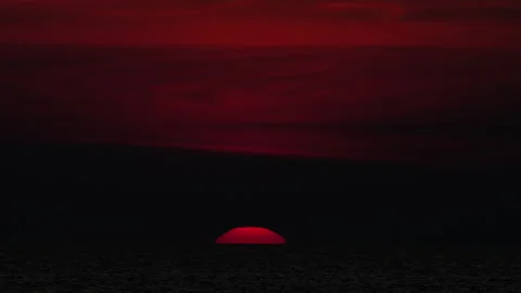 Red sun setting on sea horizon under dramatic crimson sky Stock Footage 337628956