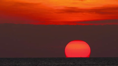 Red sun setting into sea horizon during dramatic crimson sunset Stock Footage 344694170
