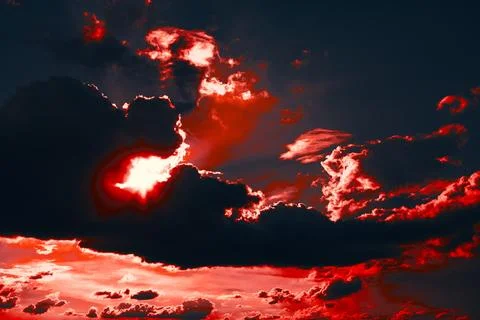 Red sun is shining through a cloud of red and black clouds 스톡 사진
