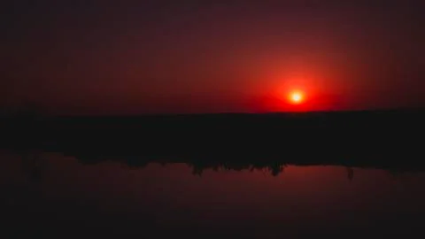 Red sun at sunset reflected in the river Stock Photos