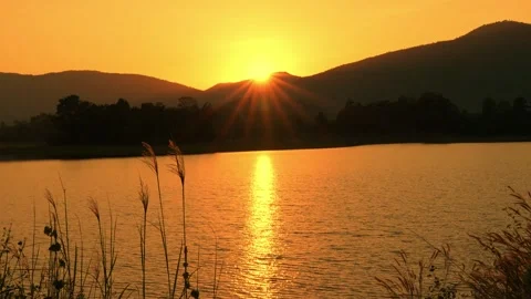 Red sunlight hits the waves in the lake before the sun sets behind the moun.. Stock Footage 256516107