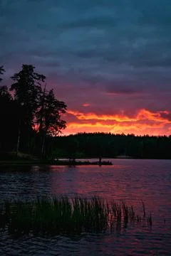 Red sunset with clouds over lake in forest in Russia Stock Photos