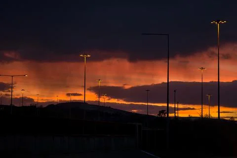 Red sunset with dark rainy clouds over the bridge with silhouettes Foto stock
