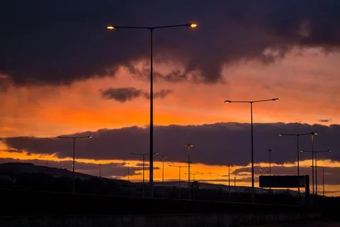 Red sunset with dark rainy clouds over the bridge with silhouettes Stock Photos