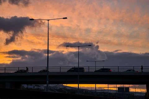 Red sunset with dark rainy clouds over the bridge with silhouettes Stock Photos