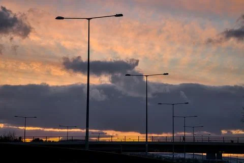 Red sunset with dark rainy clouds over the bridge with silhouettes Stock Photos