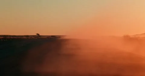 Red Sunset Dust Swirling Above Desert Road After Passing Cars Stock Footage 321773582