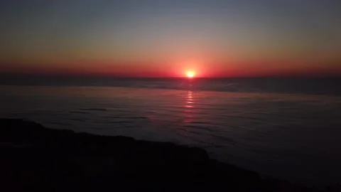 Red sunset over the ocean, small waves and calming Stockbeeldmateriaal 221379559