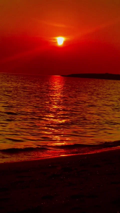 Red sunset over ocean water with vibrant sun reflection, vertical wide shot Stock Footage 345166778