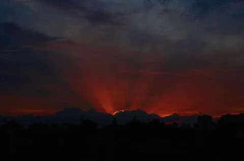 Red sunset through clouds on the blue sky horizontally Stock Photos