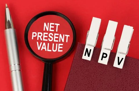 On the red surface lies a pen, a notebook with clothespins - NPV, and a magni Stock Photos