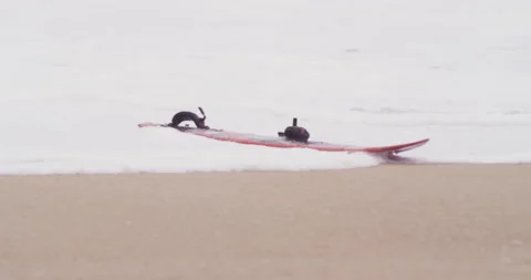 Red surfboard washed out by bubbly waves from ocean on sandy beach Stock Footage 155605730