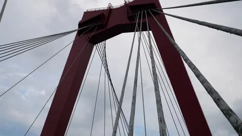 Red suspension bridge tower with dramatic cables and cloudy sky. Stock Footage 319910591