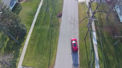 Red SUV driving down residential street, aerial view Stock Footage 49725239