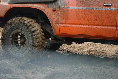 A red SUV in the mud accelerates to overcome obstacles. Off-road competitio.. Stock Photos