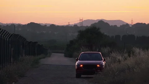 Red SUV parked on rural road with hazard lights at dusk Stock Footage 337794488