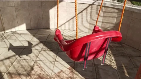 Red swing hanging from ceiling on balcony swaying with wind Stock Footage 213967299