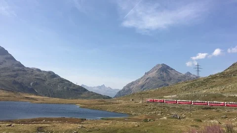 Red Swiss train passes next to a Lej Nair lake in Switzerland Stockbeeldmateriaal 81355115