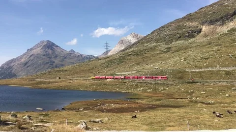 Red Swiss train passes next to a Lej Nair lake in Switzerland Stockbeeldmateriaal 81355141