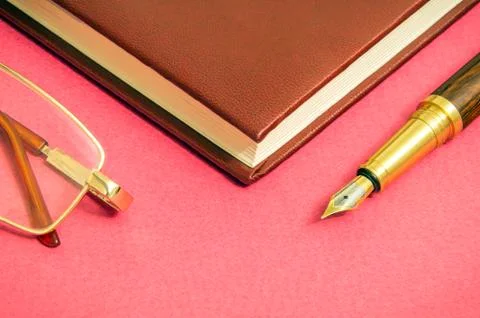 Red table with notebook a gilt pen and glasses businessman prepare for notes Stock Photos
