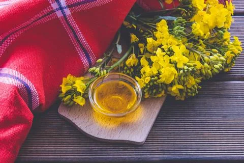 A red tablecloth and a full cup with rapeseed oil next to it are rapeseed flo Stock Photos