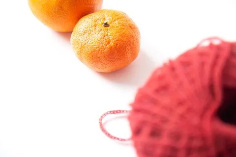 Red tangle of delicate yarn and orange tangerines isolated on white backgroun Stock Photos