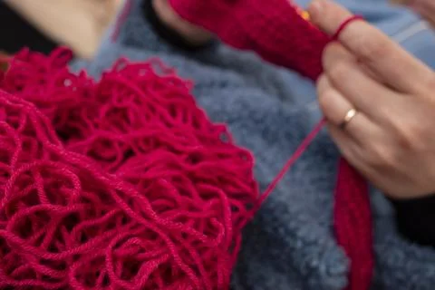 Red tangled thread with  defocused Womans  hands knitting with a crochet ho.. Stock Photos
