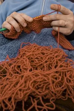 Red tangled thread with  defocused Womans  hands knitting with a crochet ho.. Stock Photos