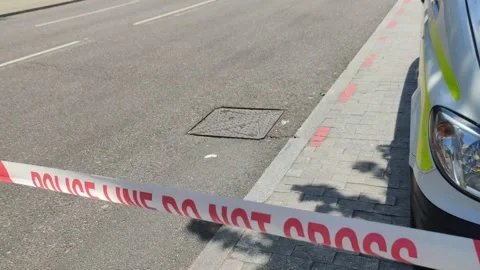 RED TAPE POLICE LINE DO NOT CROSS ON ROAD BRITISH POLICE 4K Stock Footage 154913341