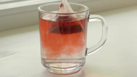 Red tea in teabag brewing in water. Close up Stock Footage 127576217