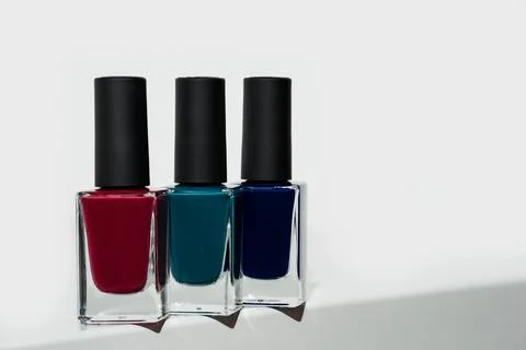 Red teal and navy blue nail polishes in a row on white Foto stock