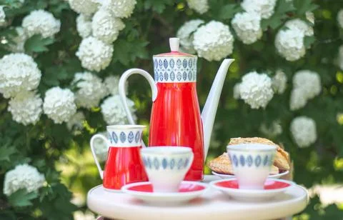 Red teapot with blue pattern teapot and two white cups on a wooden table facing Stock Photos