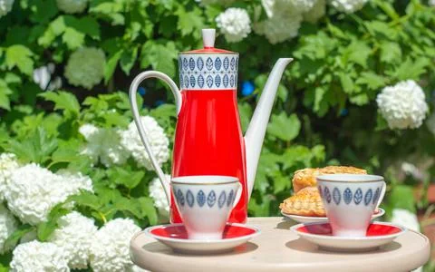 Red teapot with blue pattern teapot and two white cups on a wooden table facing Stock Photos