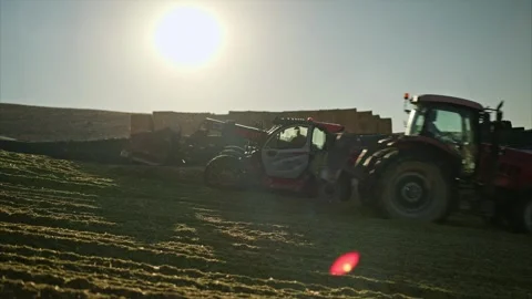 A red telehandler works under the sun, compacting silage on a farm. Stock Footage 292952421