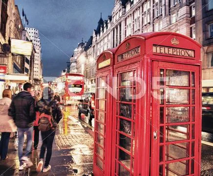 Red telephone booth in london on a crowded street at night Stock Photos