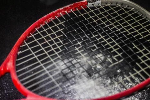 Red tennis racket strings close up with black background and white powder Photos