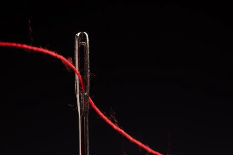 Red thread and needle on black background Foto stock