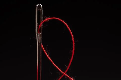 Red thread and needle on black background Stockfoto's