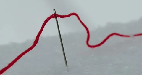 Red thread and needle in snow Stock Footage 261591268