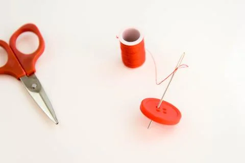 Red thread, needle, button and scissors Foto stock