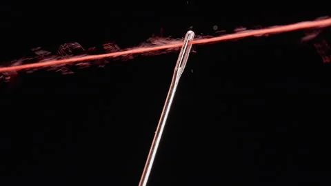 Red Thread Passes Through a Metal Needle Eye Against a Black Background, Macro V Stockbeeldmateriaal 341416498