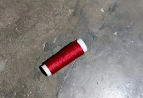 Red thread spool lying on pavement Stock Photos