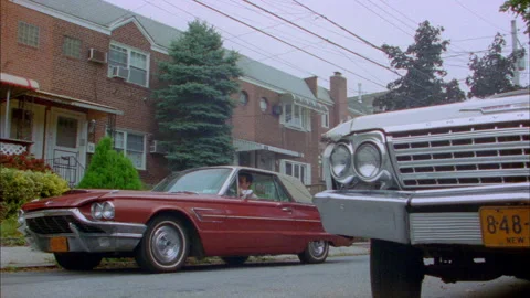Red Thunderbird comes down street and a man gets out Stock Footage 272259540