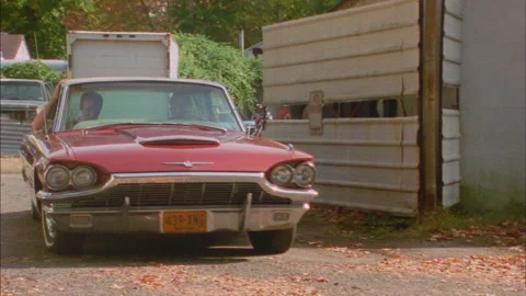 A Red Thunderbird turns out of a backlot and goes down the street Stock Footage 272271761
