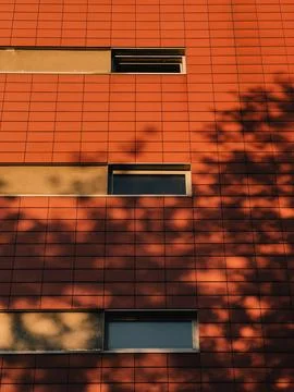 Red Tiled Building Facade with Tree Shadows at Sunset. Warm sunlight Foto stock
